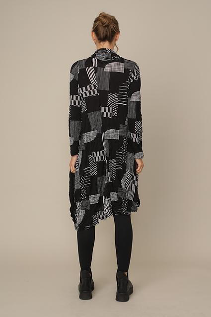 Person wearing a long, patterned shirt dress on a beige background