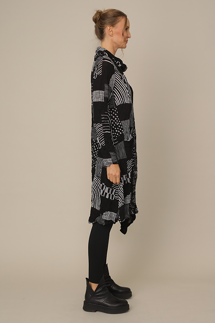 Woman wearing a black patterned dress against a beige background