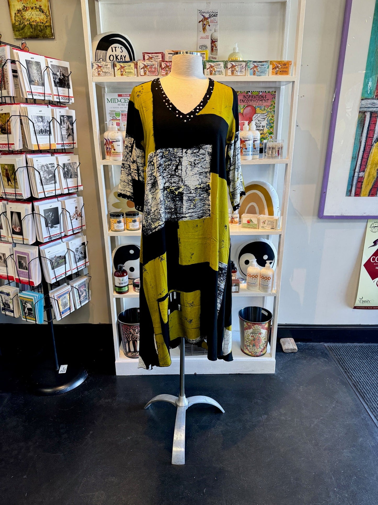 Mannequin wearing a long, patterned dress in a store setting with books and decor at Victoria Susan in Camden SC