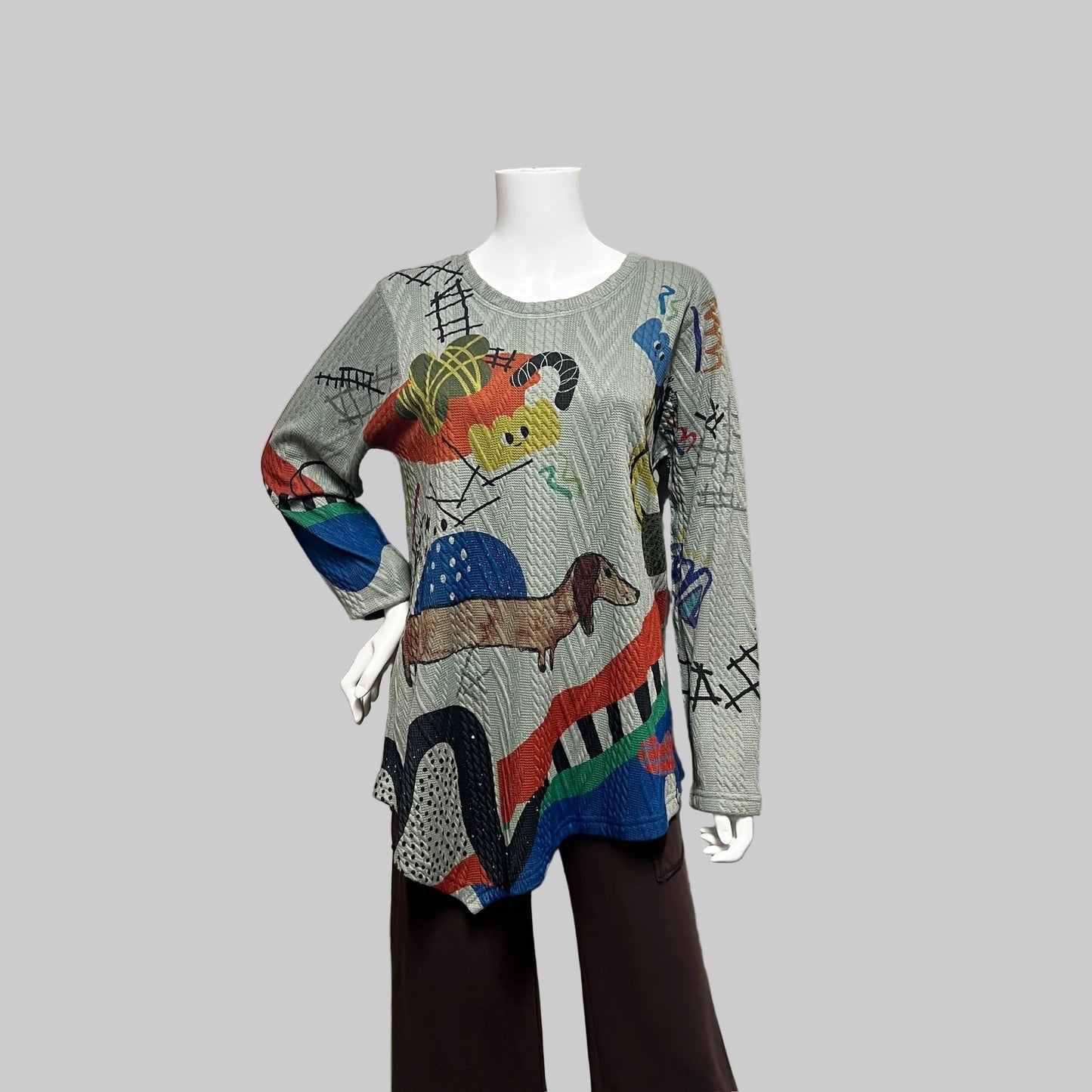 Colorful sweater with animal designs on a mannequin against a plain background