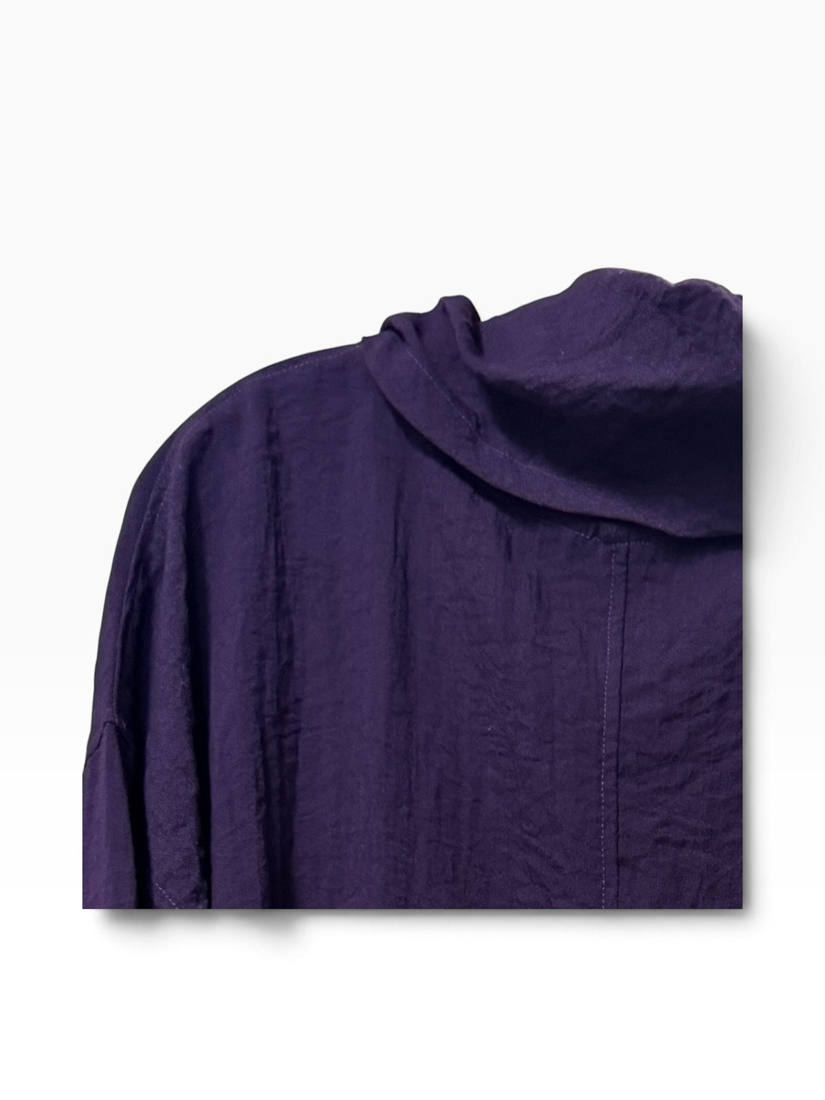 A close-up of a dark purple crinkled fabric garment, showing the texture and draped collar detail against a clean white background.