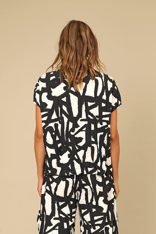 Person wearing a black and white abstract patterned dress on a beige background
