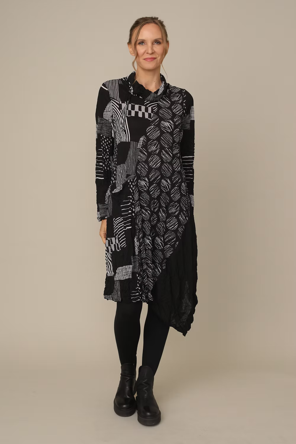 Woman wearing a long, patterned black and gray scarf against a beige background