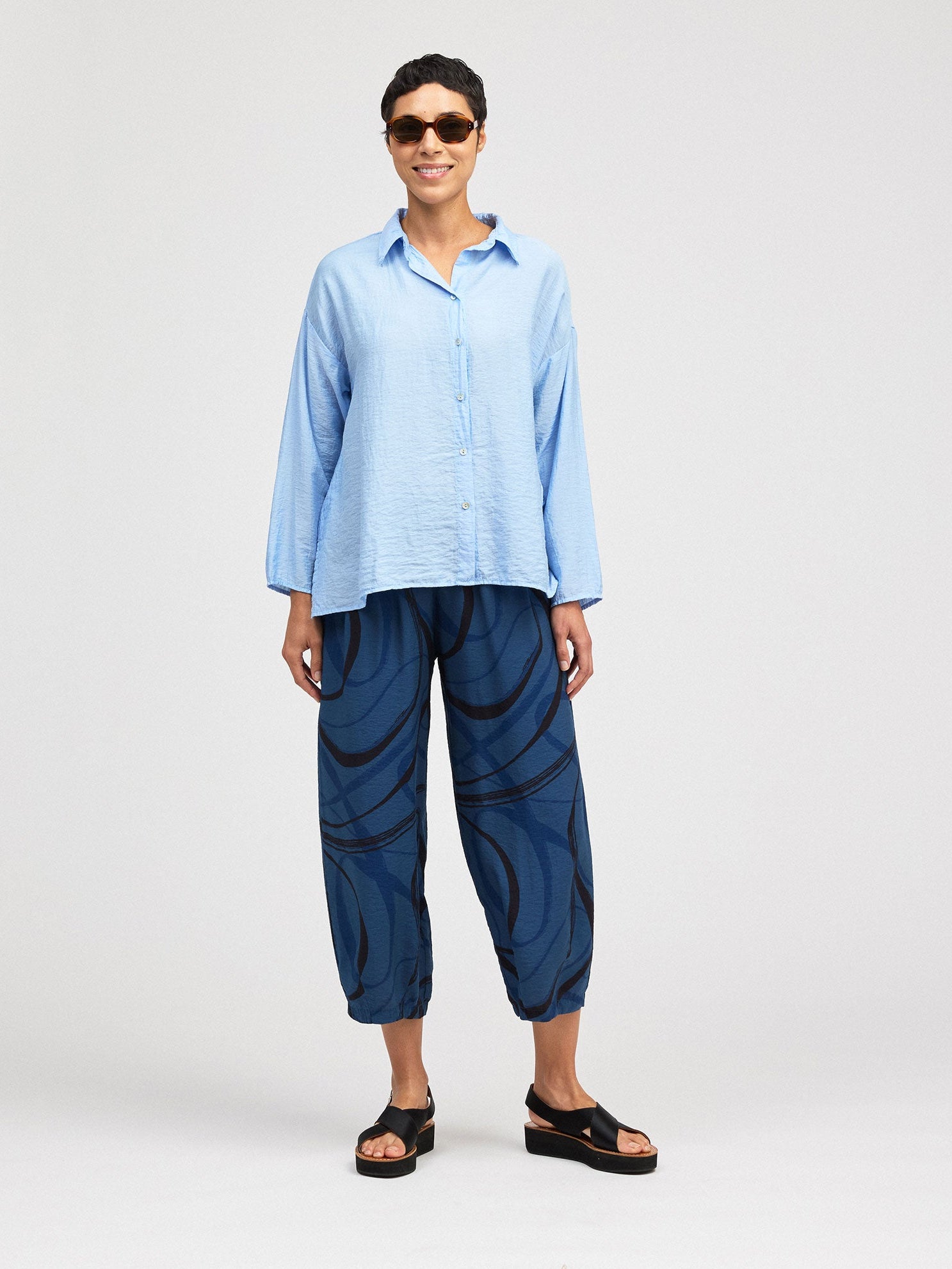 Person wearing a light blue shirt and dark blue pants on a white background