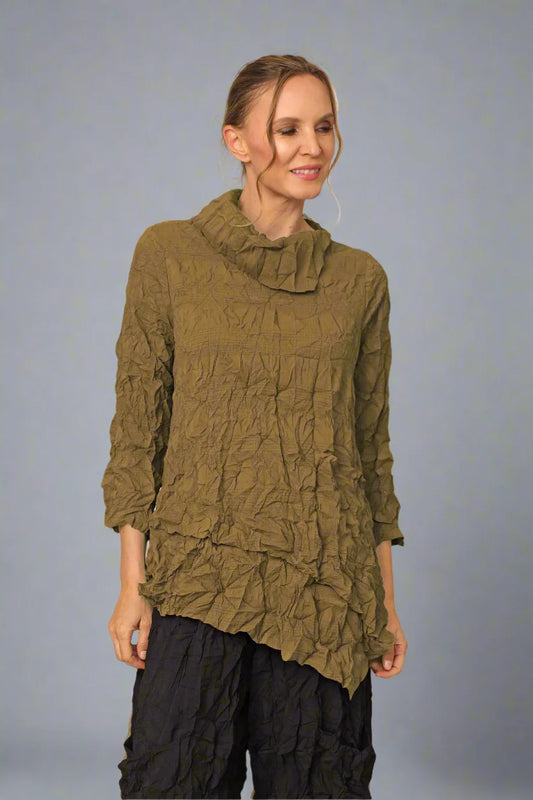 Woman wearing a textured green top and black pants against a plain background