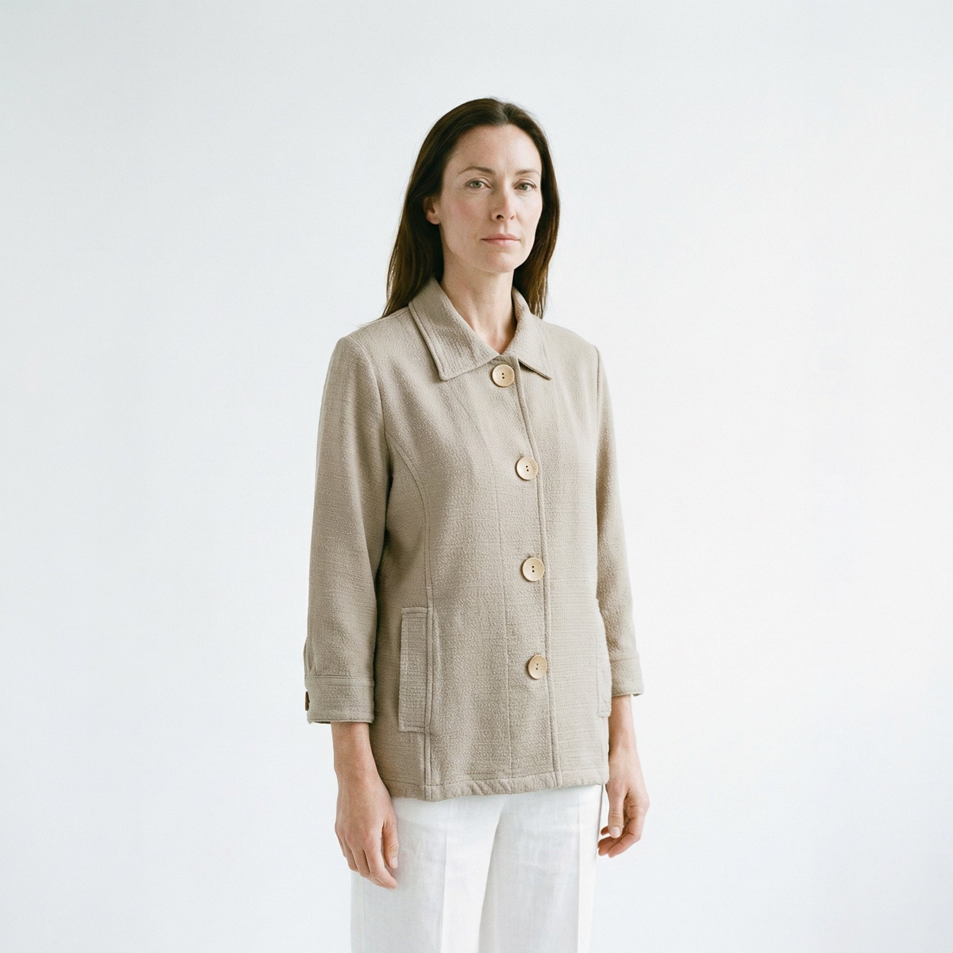 Woman wearing a beige jacket with gold buttons on a white background