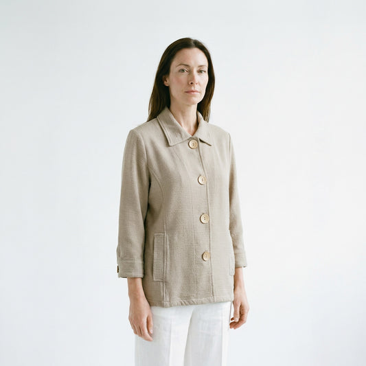 Woman wearing a beige jacket with gold buttons on a white background