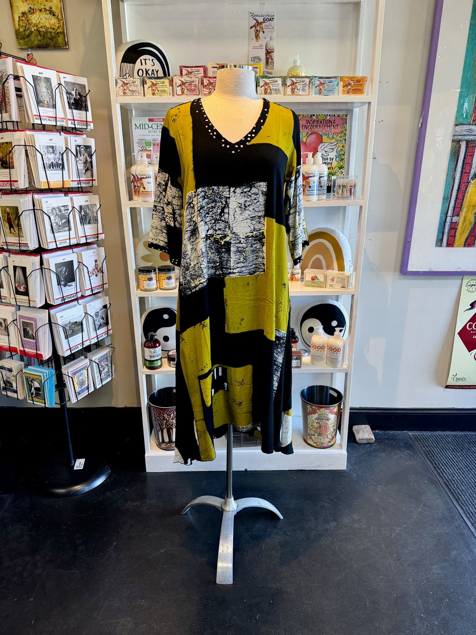 Mannequin wearing a long, patterned dress in a store setting with books and decor at Victoria Susan in Camden SC