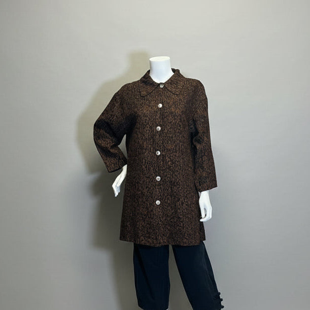 Mannequin wearing a brown coat and black pants against a plain backdrop in an indoor setting.