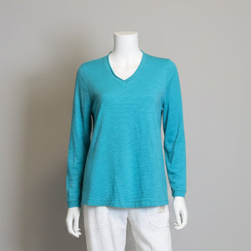 Mannequin wearing a teal long-sleeve shirt against a gray background