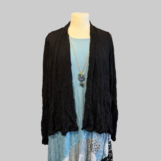 Mannequin wearing a black cardigan and blue dress with a white shelf displaying various items in the background.