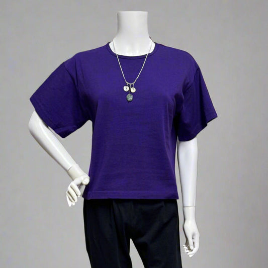 Mannequin wearing a purple shirt and black pants against a beige background