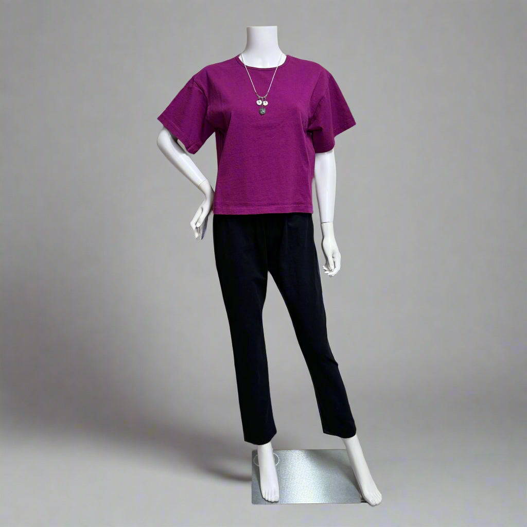 Mannequin at Victoria Susan in Camden SC wearing a purple tee by Pacificotton and black Sunday pants against a backdrop. Shop women's clothing in Camden SC. 