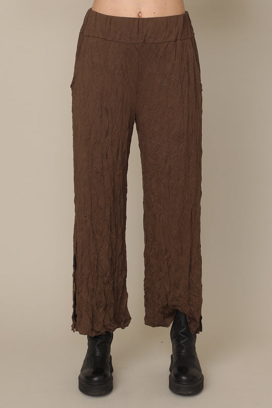 Brown textured pants worn by a person on a beige background at Victoria Susan Wearable Art in Camden SC
