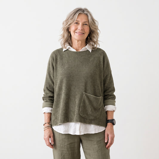 An older woman stands against a plain white studio background wearing an olive green knit sweater over a white collared shirt, with matching olive pants and bracelets. squirrel in One Size Marled Knit Sweater by Cut-Loose 